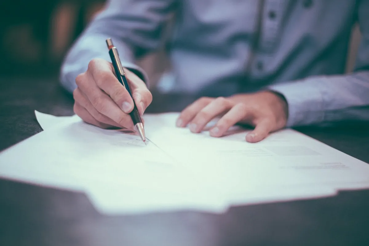 Hands writing on a document at a desk